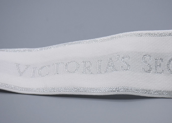De kleding paste 35mm Witte Jacquard Elastische Band met Glanzend Zilveren Embleem aan